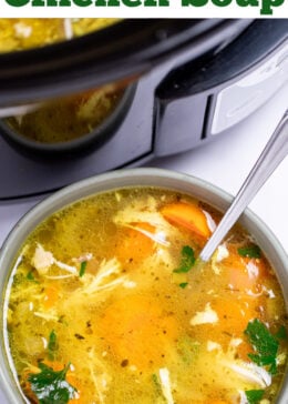 Pinterest pin with a bowl of chicken soup on a table with a spoon in it, in front of a slow cooker of soup.