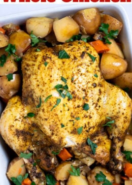 Pinterest pin with a whole chicken, broiled until crispy, resting on top of potatoes and carrots in a baking dish, topped with fresh parsley.