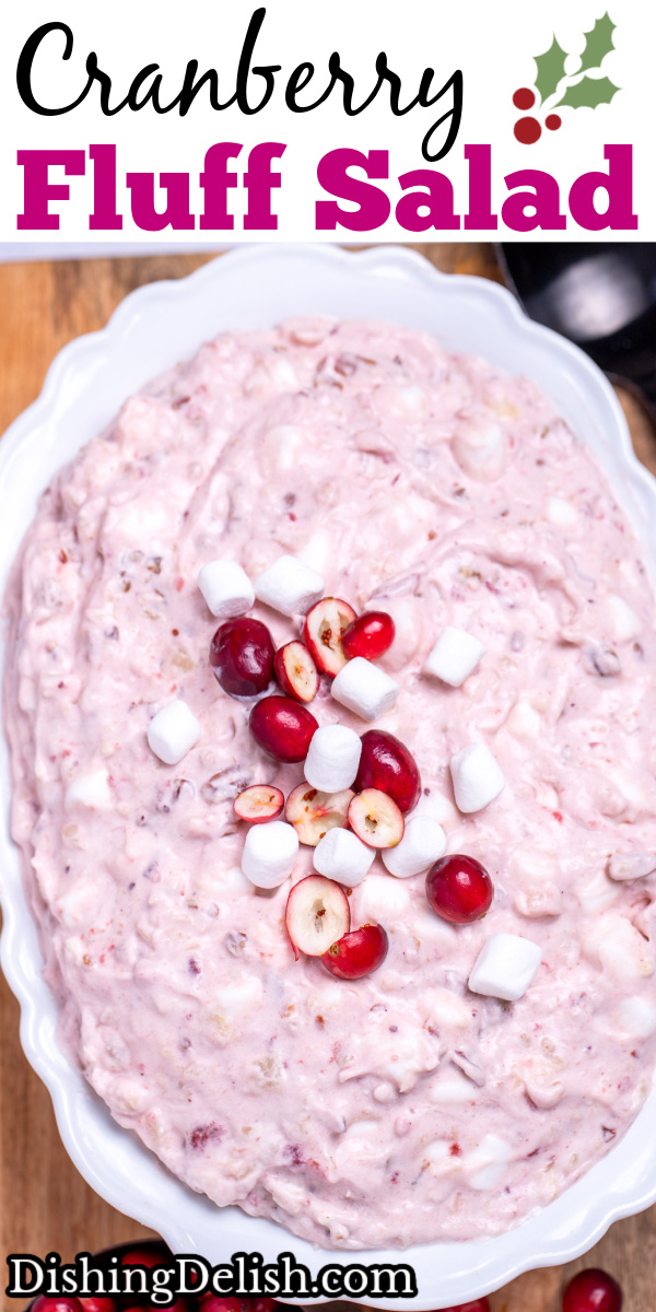 Pinterest pin with a serving bowl with cranberry fluff salad topped with mini marshmallows and fresh cranberries, resting on a cutting board, next to a cup of fresh cranberries and a serving spoon.