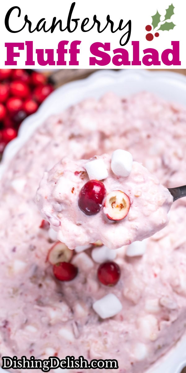Pinterest pin with a serving bowl with cranberry fluff salad topped with mini marshmallows and fresh cranberries, resting on a cutting board, next to a cup of fresh cranberries and a serving spoon lifting some fluff up.
