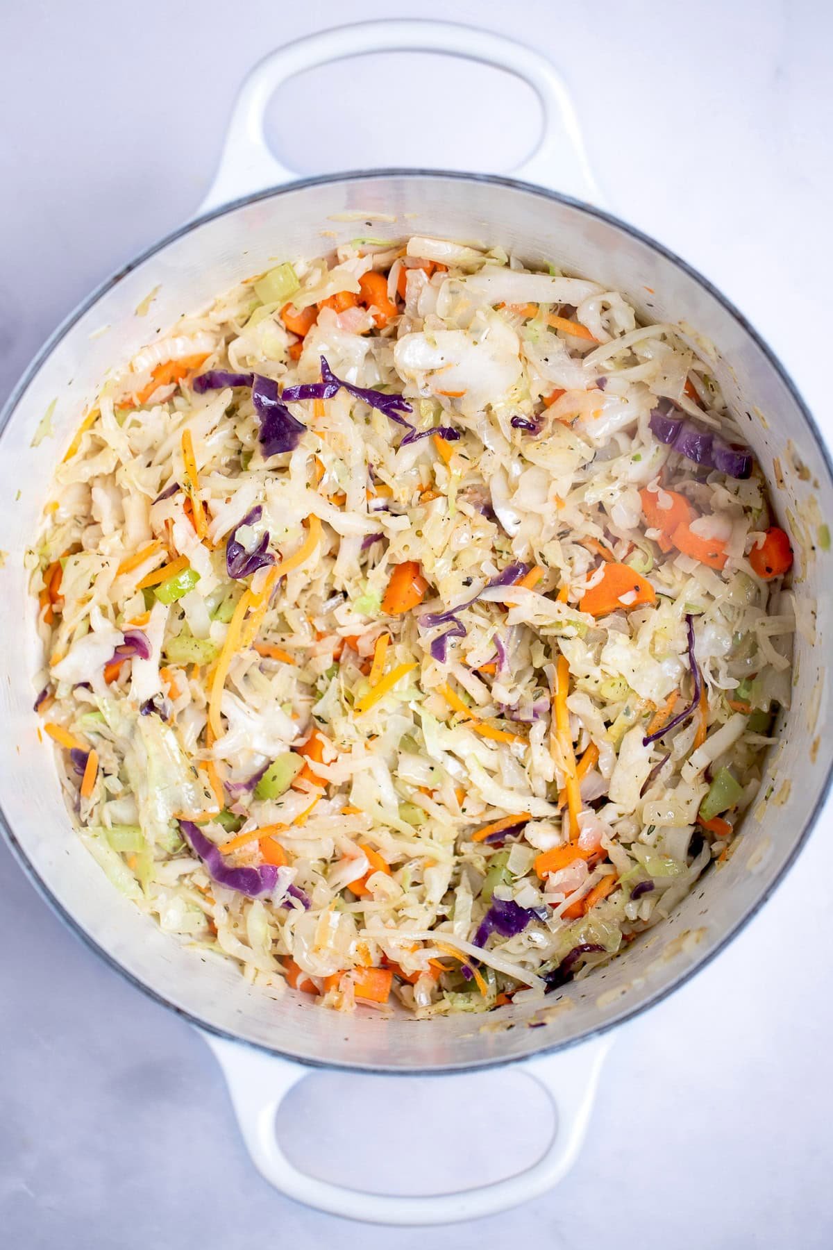 A dutch oven with sautéed coleslaw mix in it.