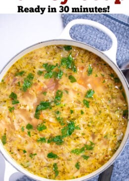 Pinterest pin with a dutch oven on a table with turkey soup topped with fresh parsley, next to a towel with a ladle on it on the table.