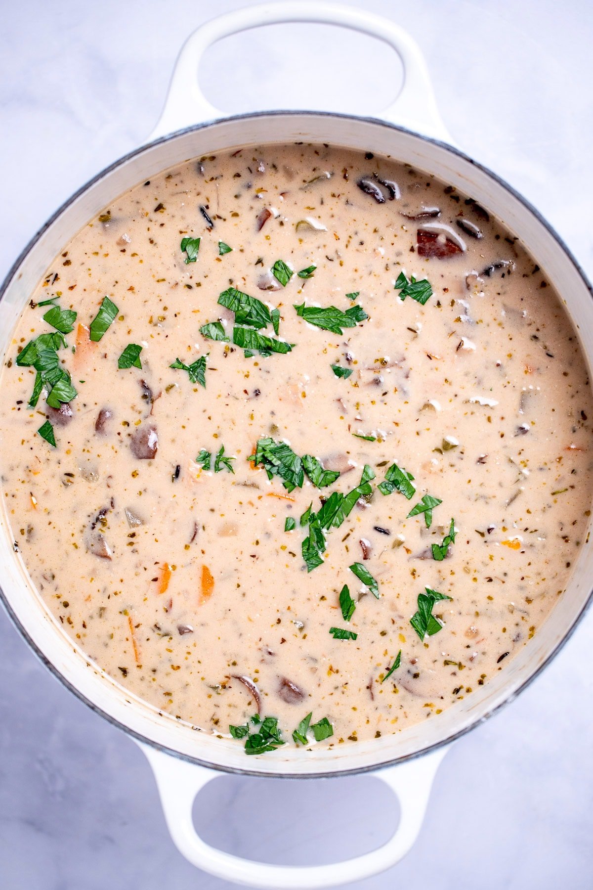 Delicious homemade creamy leftover turkey and wild rice soup garnished with fresh parsley in a dutch oven.