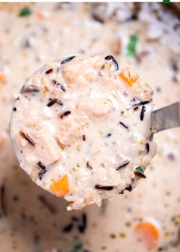 Pinterest pin with delicious homemade creamy leftover turkey and wild rice soup garnished with fresh parsley in a dutch oven, with a ladle lifting some up.