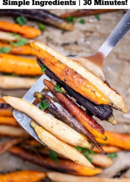 Pinterest pin with a spatula lifting roasted rainbow carrots from a sheet pan lined with parchment paper.