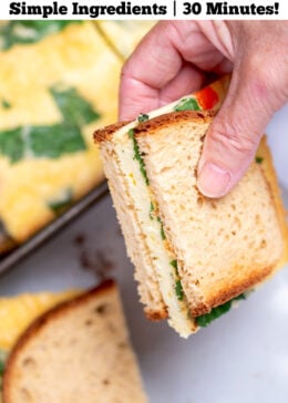 Pinterest pin with a piece of sheet pan eggs in a breakfast sandwich, with half being held by a hand.