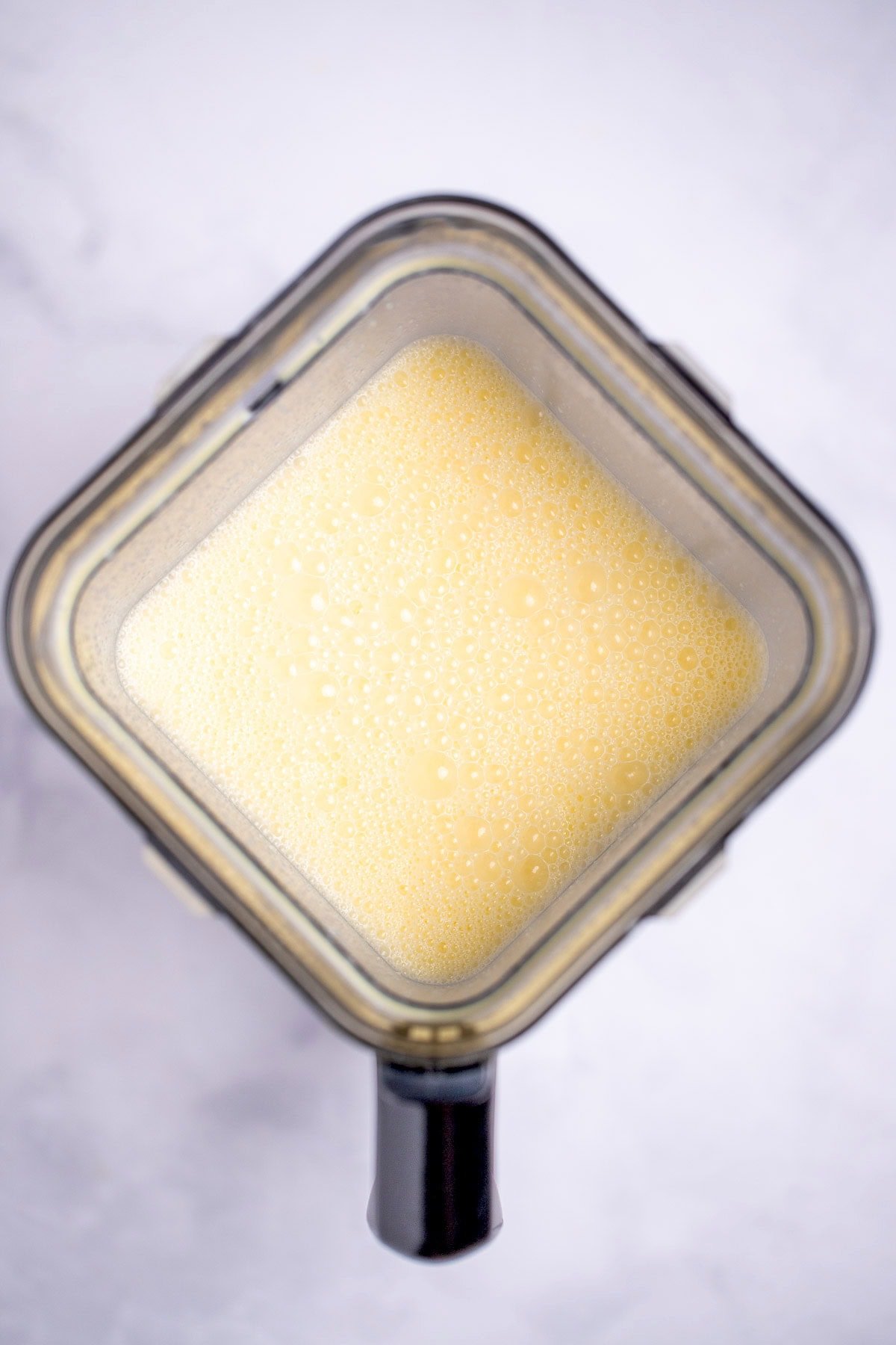 A blender with blended eggs, half & half, and parmesan.