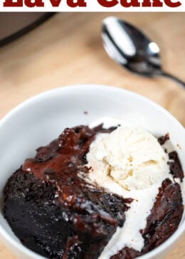 Pinterest pin with a bowl of chocolate lava cake topped with ice cream and a spoon, in front of a slow cooker on a table.