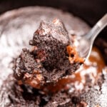 A slow cooker with chocolate lava cake, and a spoon lifting some up.