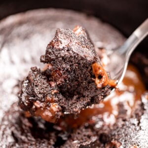A slow cooker with chocolate lava cake, and a spoon lifting some up.