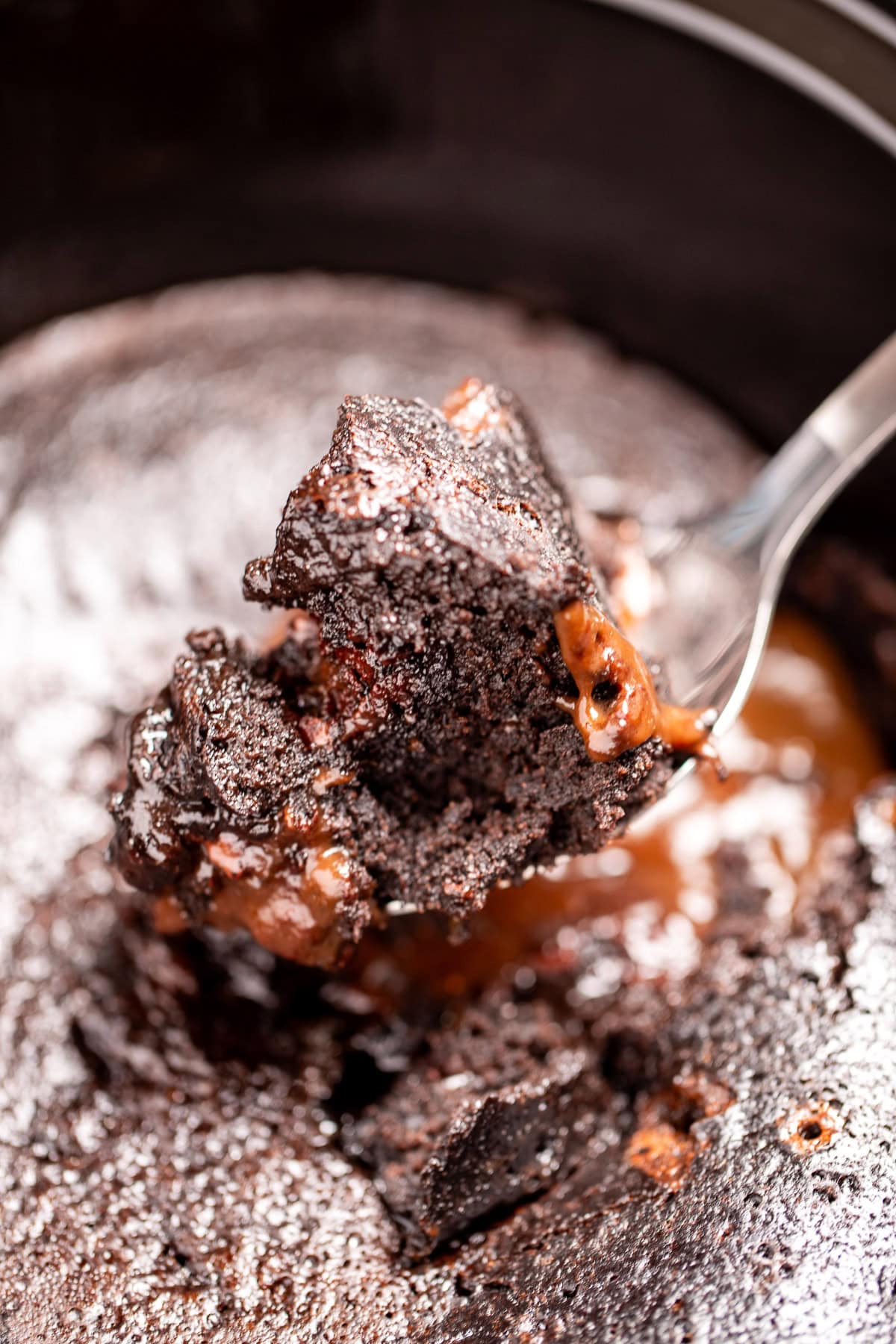 A slow cooker with chocolate lava cake, and a spoon lifting some up.