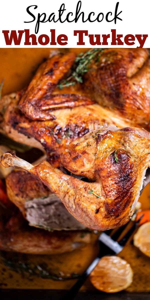 Pinterest pin with a roasting pan with a golden brown spatchcocked turkey resting on top of lemon and vegetables, with melted butter and fresh thyme on the bottom of the pan, and a turkey leg being lifted up by a spatula.
