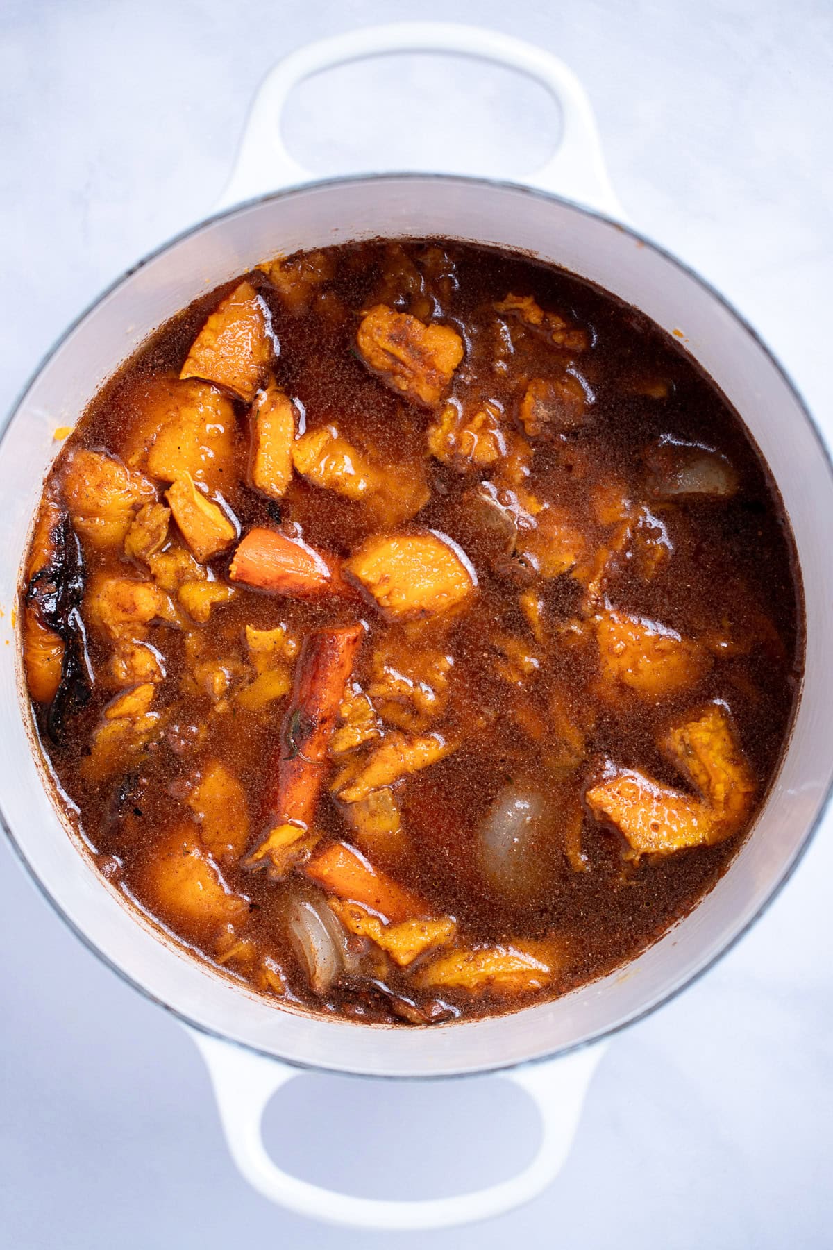 A dutch oven with broth and roasted vegetables before being pureed.