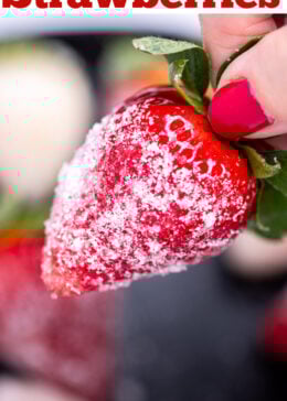 A hand holding a sugar coated champagne strawberry.