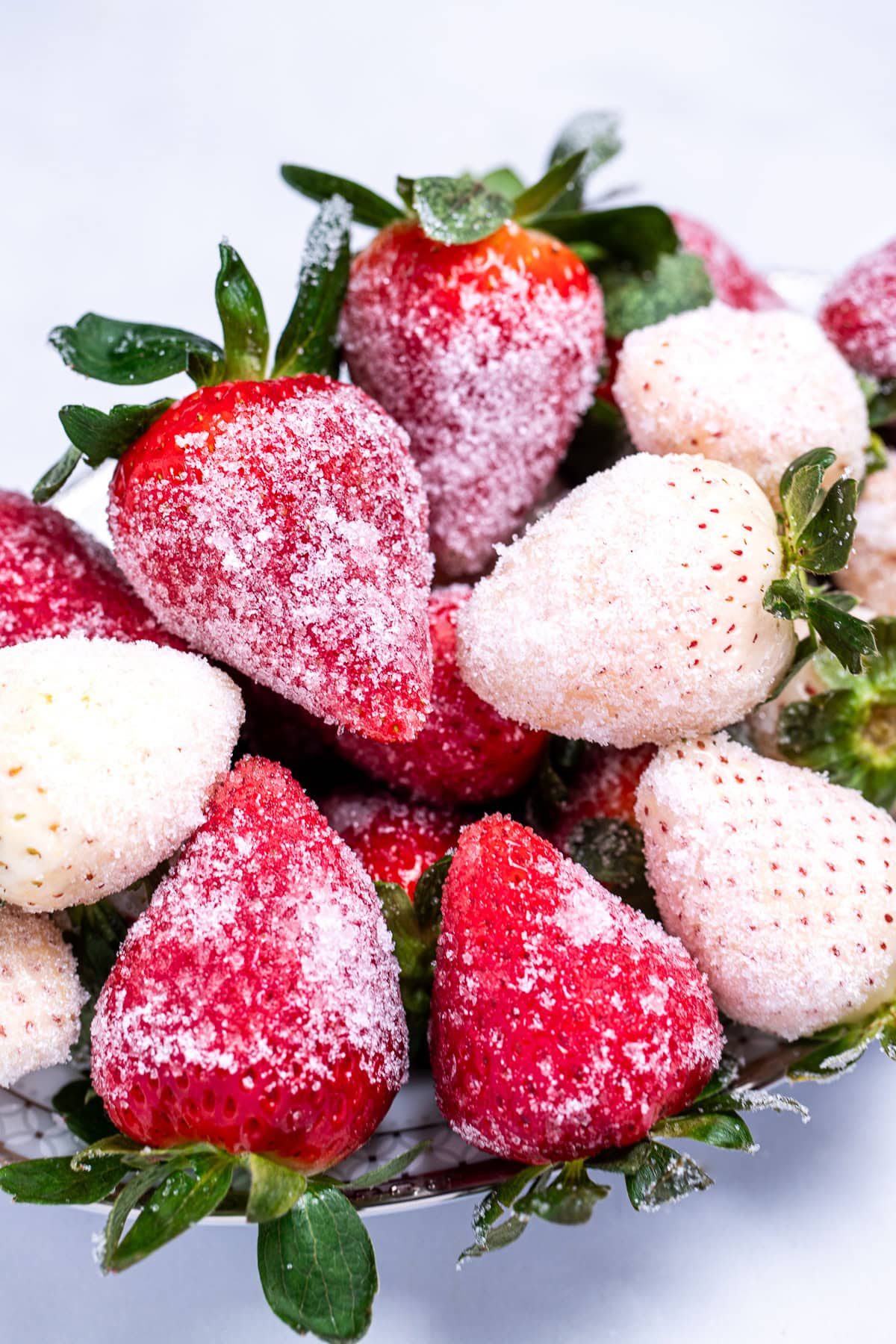 Red and white sugar coated champagne strawberries on a plate.