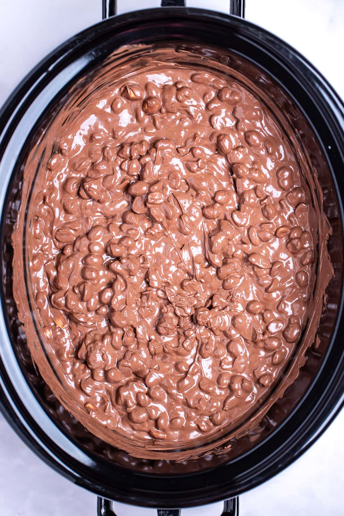 A slow cooker with peanuts mixed with melted chocolate.