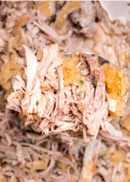 Pinterest pin with a spoon lifting up shredded pork shoulder and sauerkraut from a slow cooker.