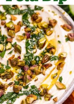 Pinterest pin with a bowl of whipped feta dip topped with chopped parsley, pistachios, olive oil, and honey on a wooden cutting board.