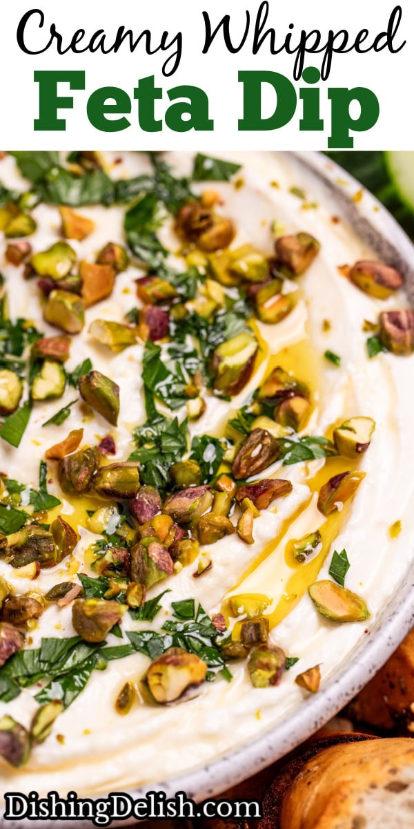 Pinterest pin with a bowl of whipped feta dip topped with chopped parsley, pistachios, olive oil, and honey on a wooden cutting board.