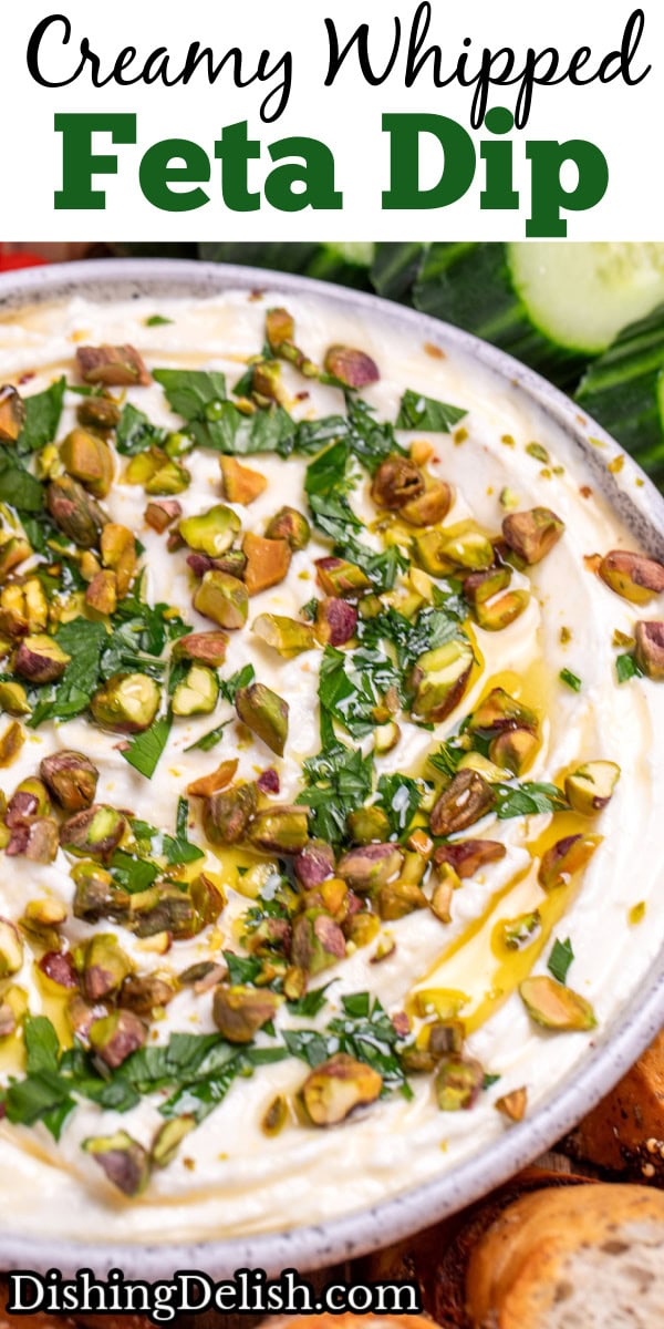 Pinterest pin with a bowl of whipped feta dip topped with chopped parsley, pistachios, olive oil, and honey on a wooden cutting board.