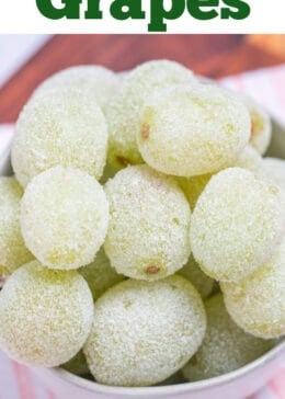 Pinterest pin with a bowl of sugared grapes on a tea towel on a wooden cutting board.