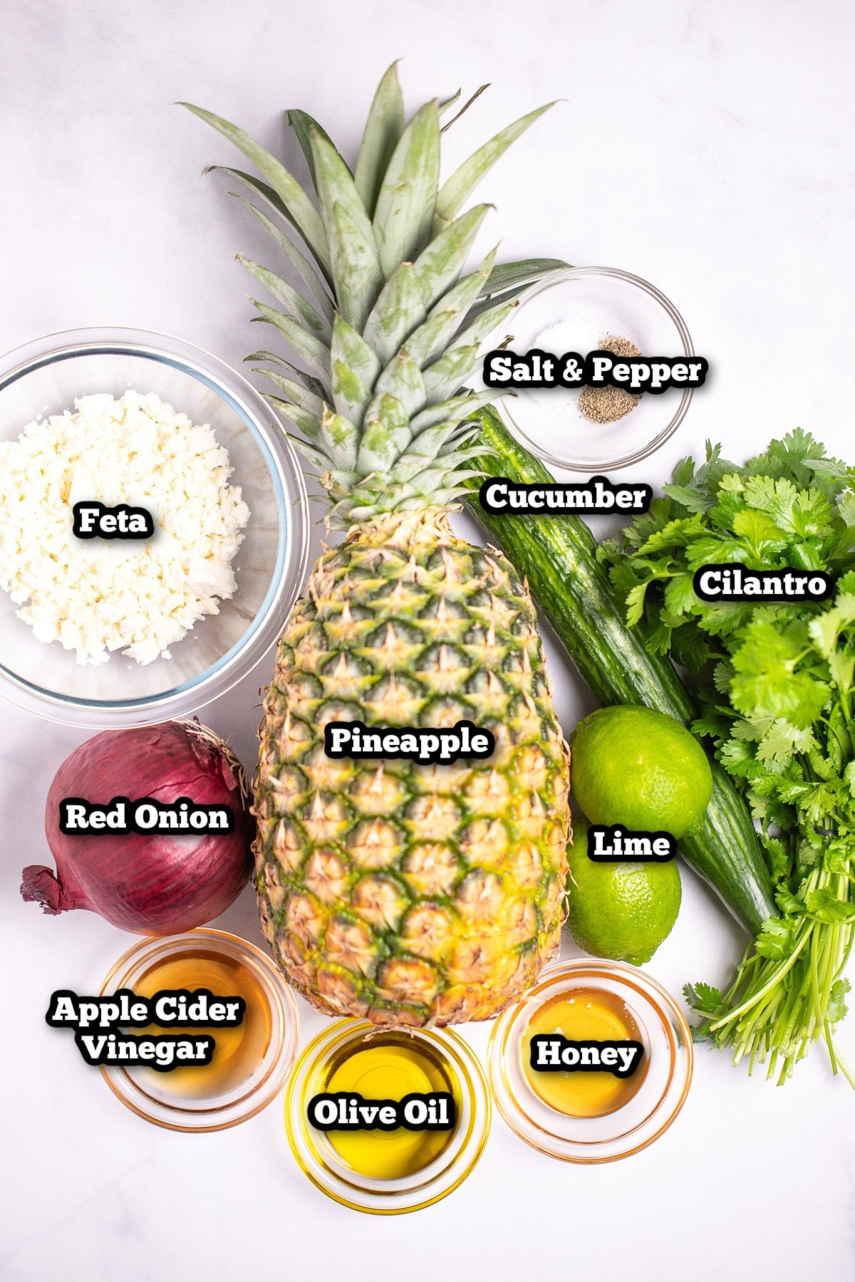Individual ingredients for pineapple cucumber salad on a table.