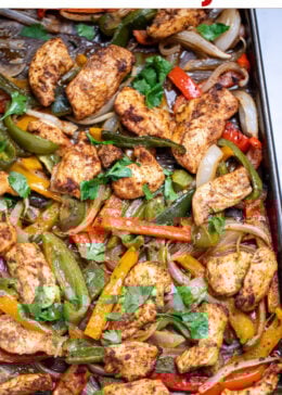 Pinterest pin with a sheet pan lined with parchment paper with cooked chicken and peppers topped with fresh cilantro.