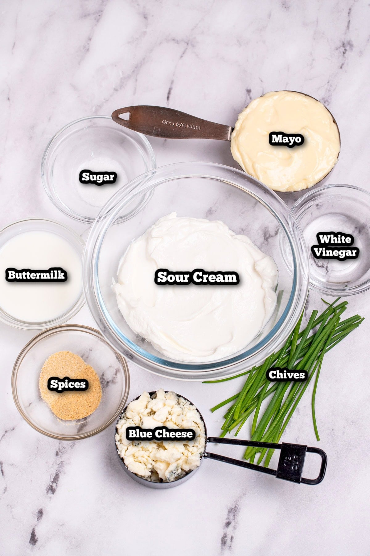 Individual ingredients for homemade blue cheese dressing on a table.