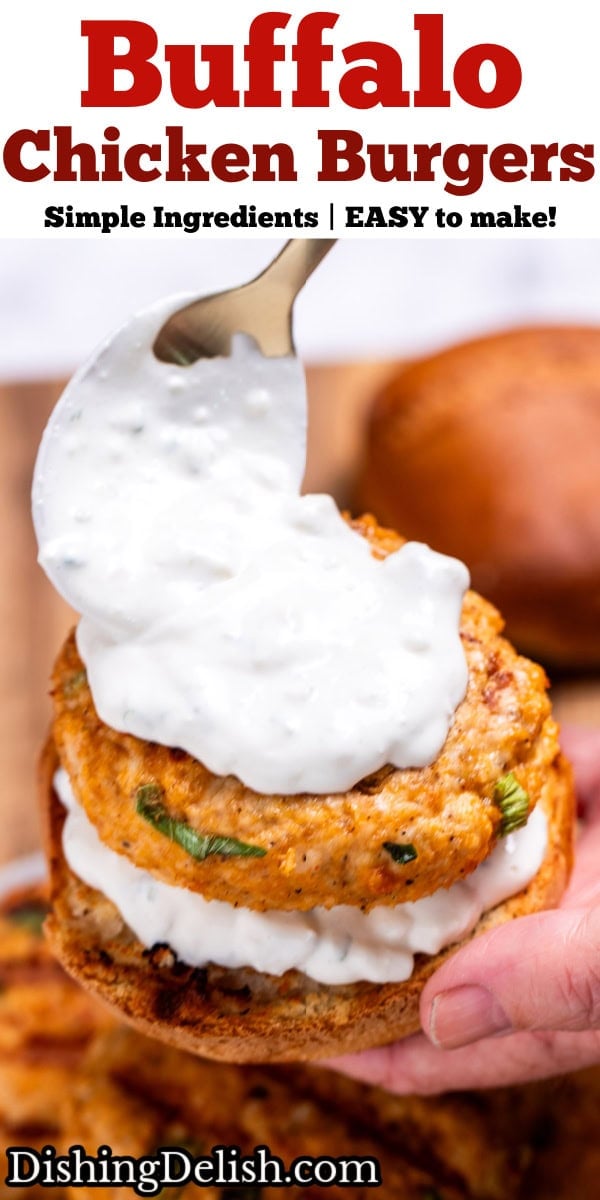 Pinterest pin with a hand holding a buffalo chicken burger with a spoon placing blue cheese dressing on the burger, over a plate of burger patties.