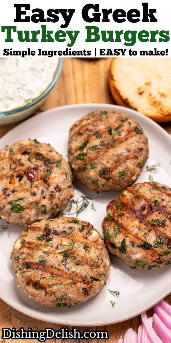 Pinterest pin with a plate resting on a cutting board, with four grilled greek turkey burgers, next to red onion, a burger bun, and a bowl of tzatziki on the board.