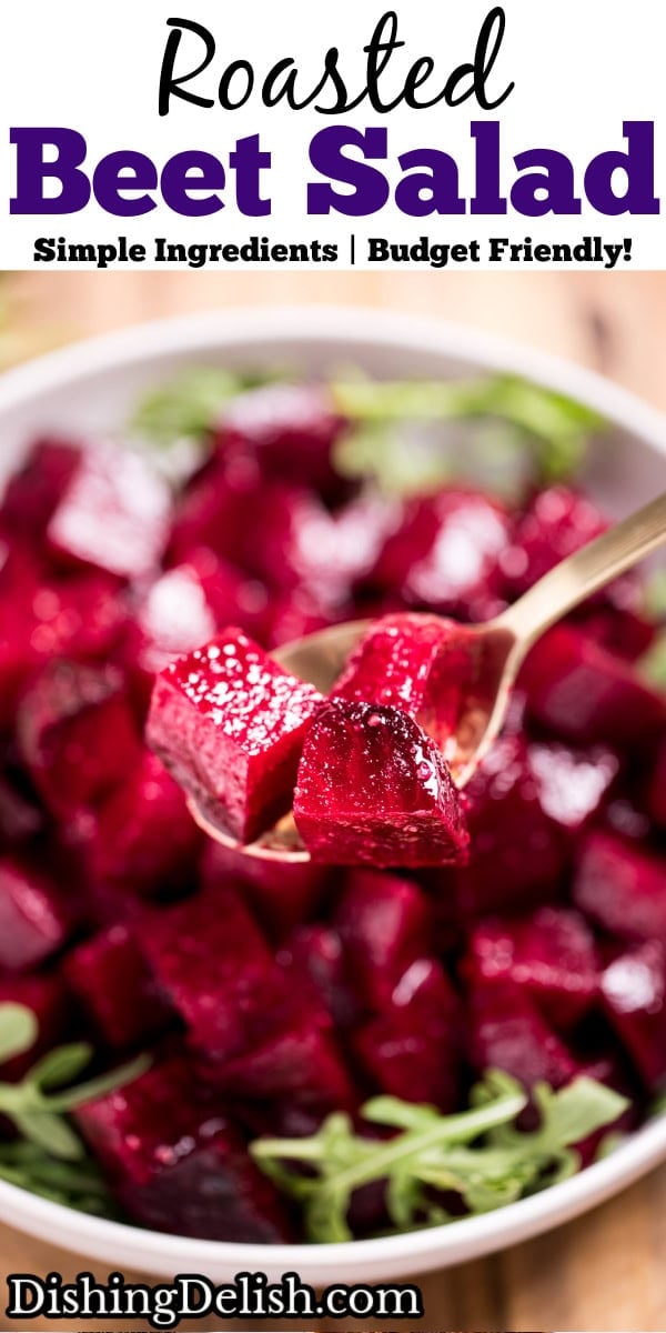 Pinterest pin with a bowl of roasted beet salad resting on arugula, on a cutting board, with a spoon lifting some beet pieces up.