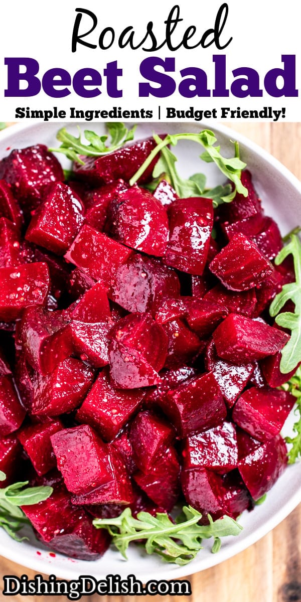 Pinterest pin with a bowl of roasted beet salad resting on arugula, on a cutting board.