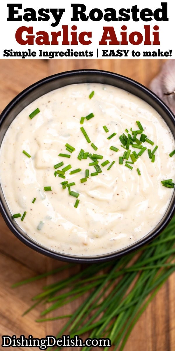 Pinterest pin with a small bowl of roasted garlic aioli topped with fresh chives, on a cutting board next to more chives and a bulb of garlic.