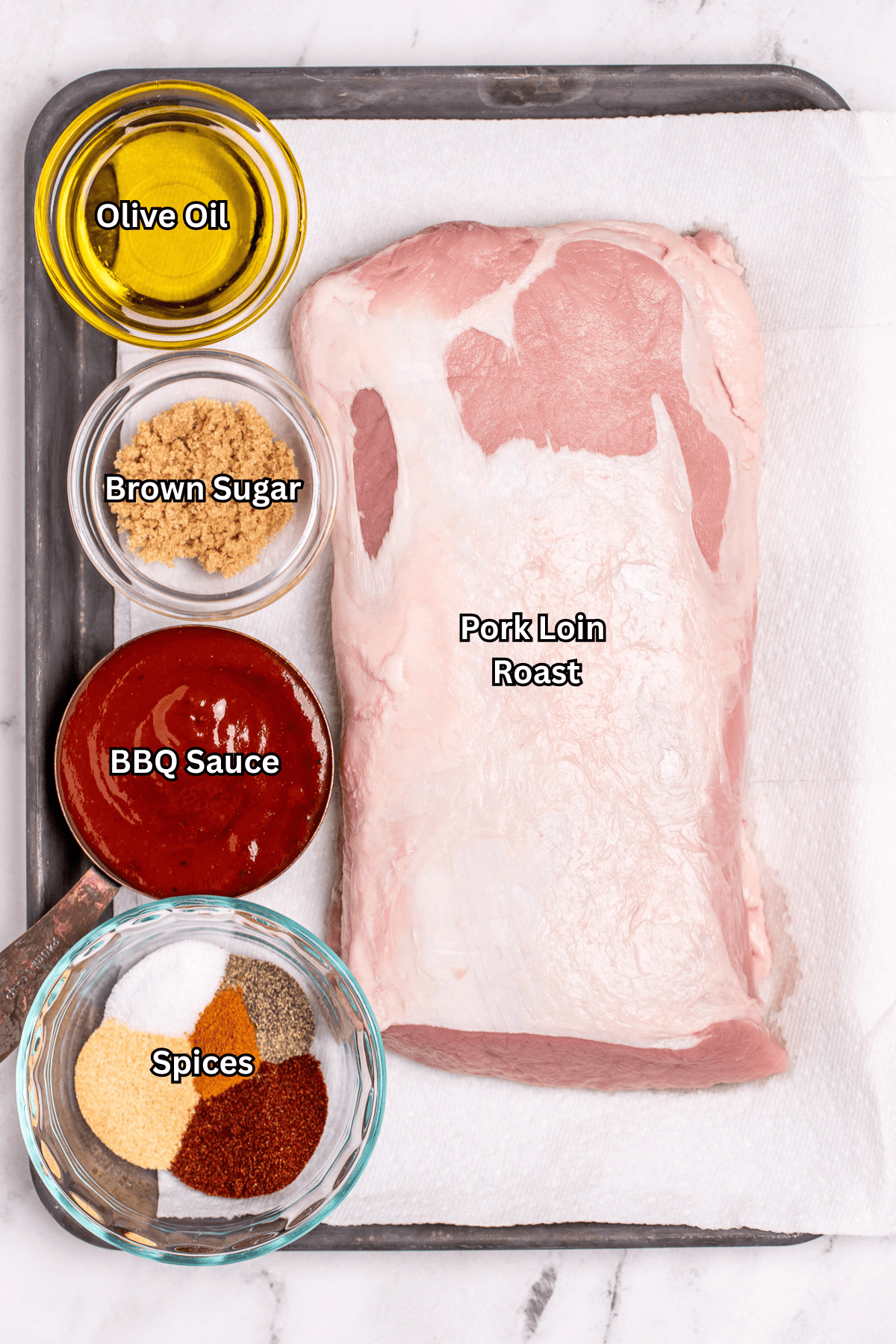 Individual ingredients for grilled pork loin on a sheet pan, on a table.