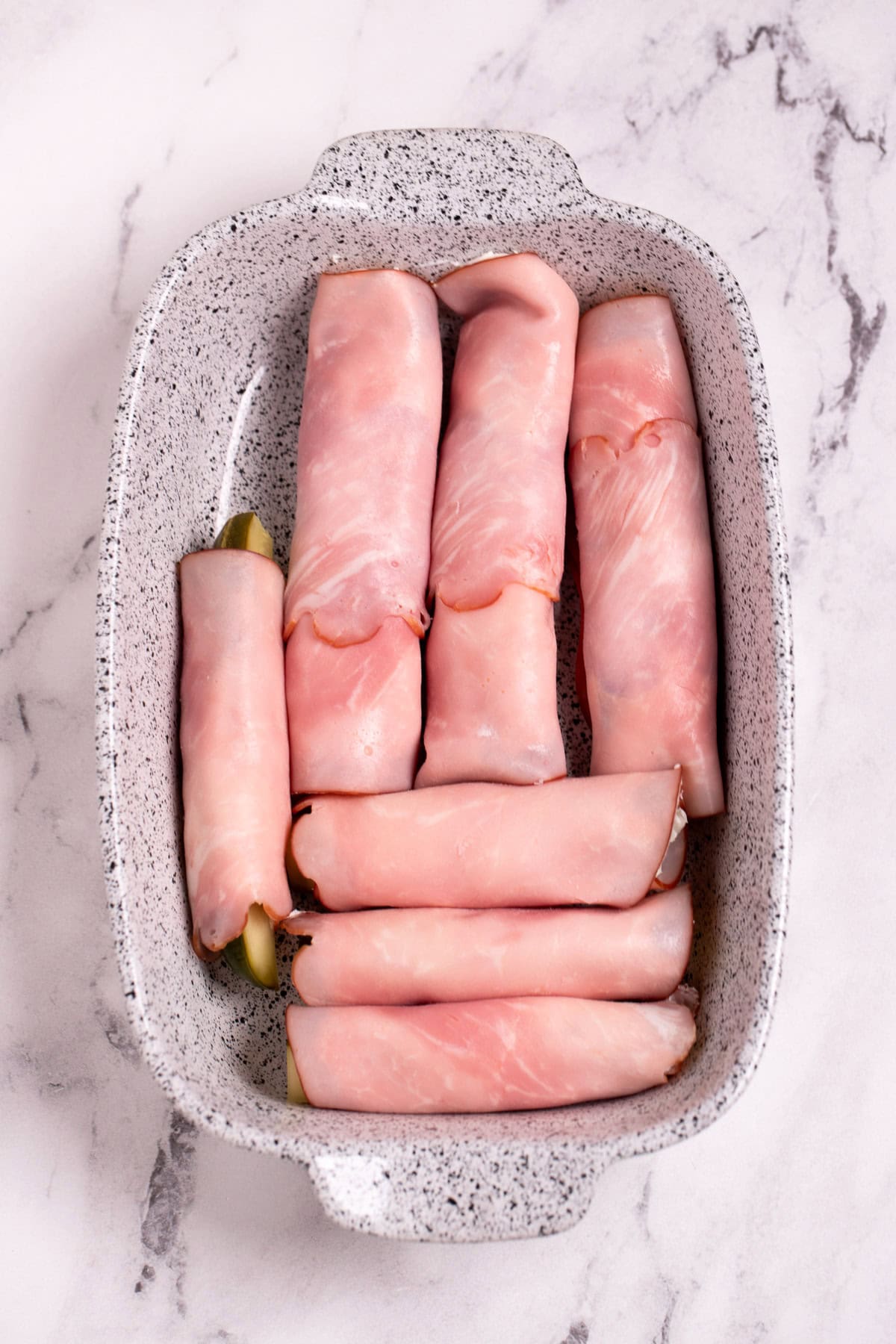 A dish with dill pickle roll ups before being sliced into pieces.