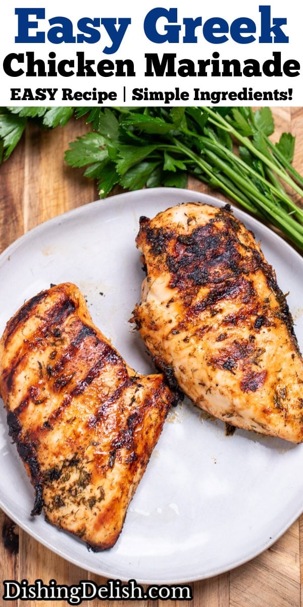 Pinterest pin with a Greek marinated chicken breast resting on a plate on a cutting board next to fresh parsley.