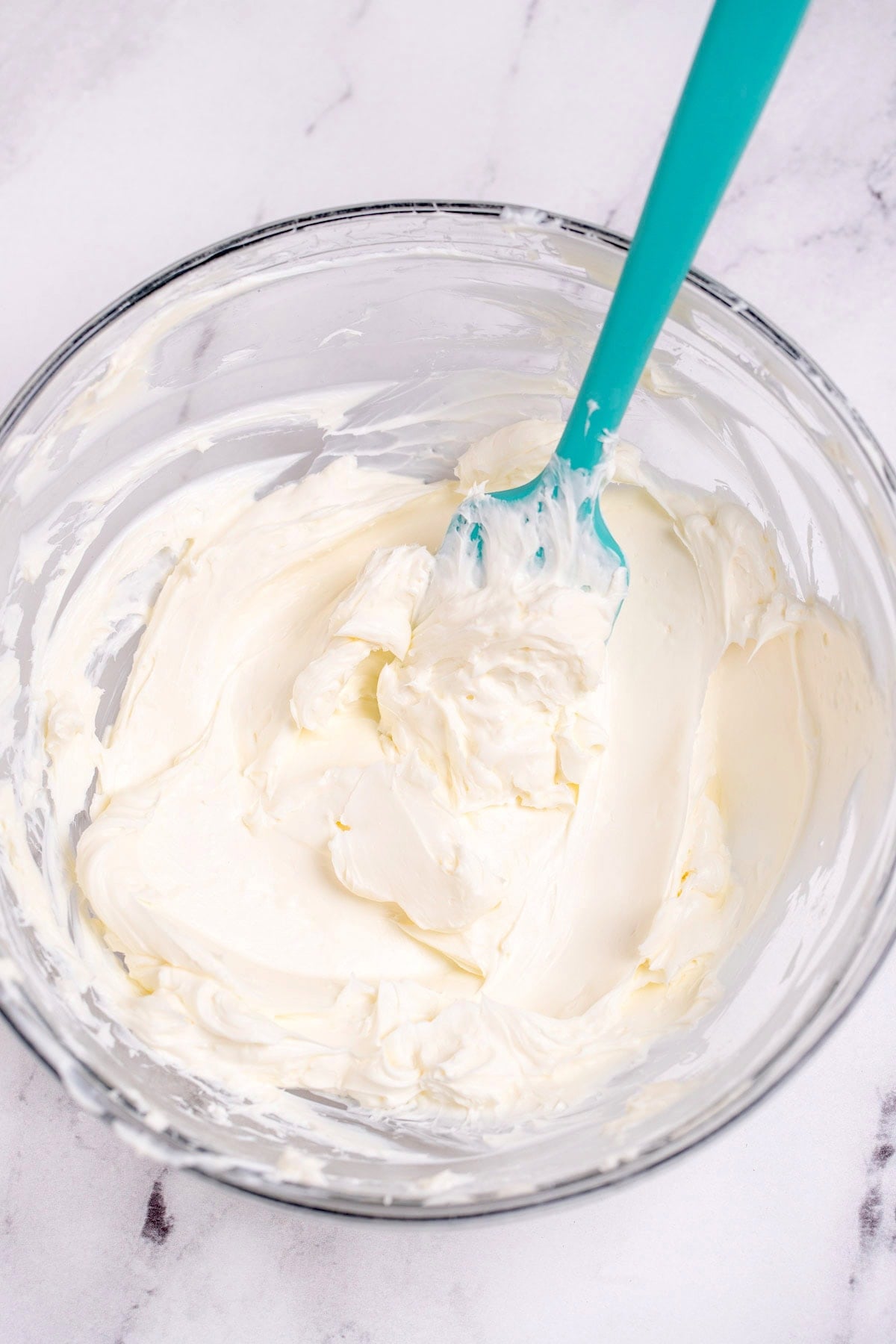 A glass bowl of whipped cream cheese on a table.