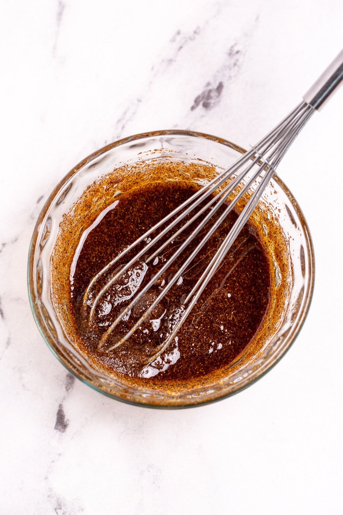 A small bowl of oil and seasoning being whisked together.