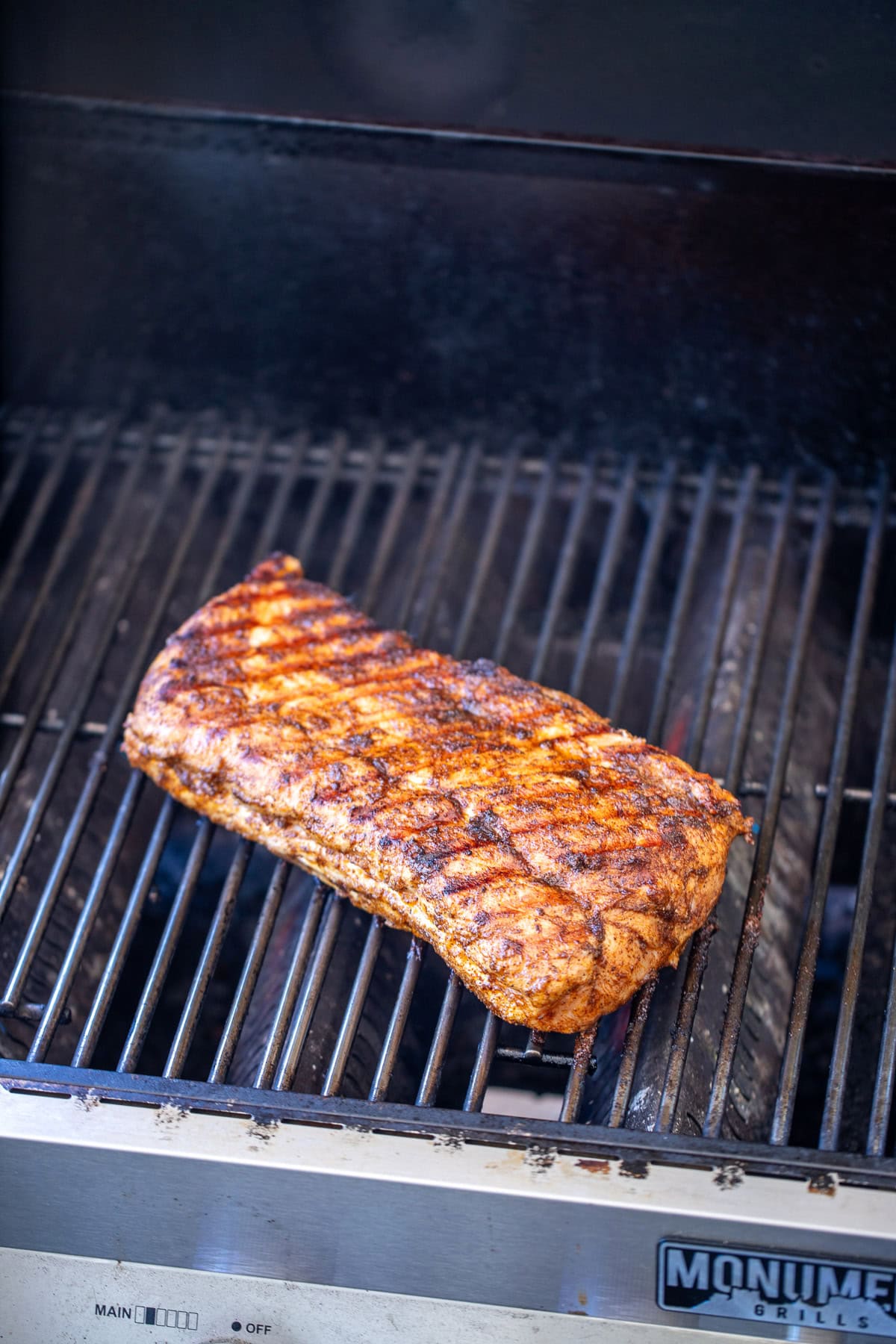 A grill with a pork loin on it with grill marks.