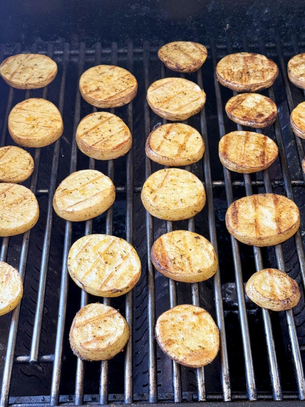 Potato slices on a grill while cooking.