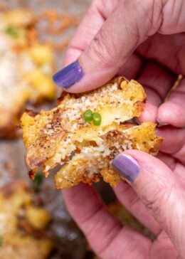 Two hands holding a garlic parmesan smashed potato while breaking it in half.