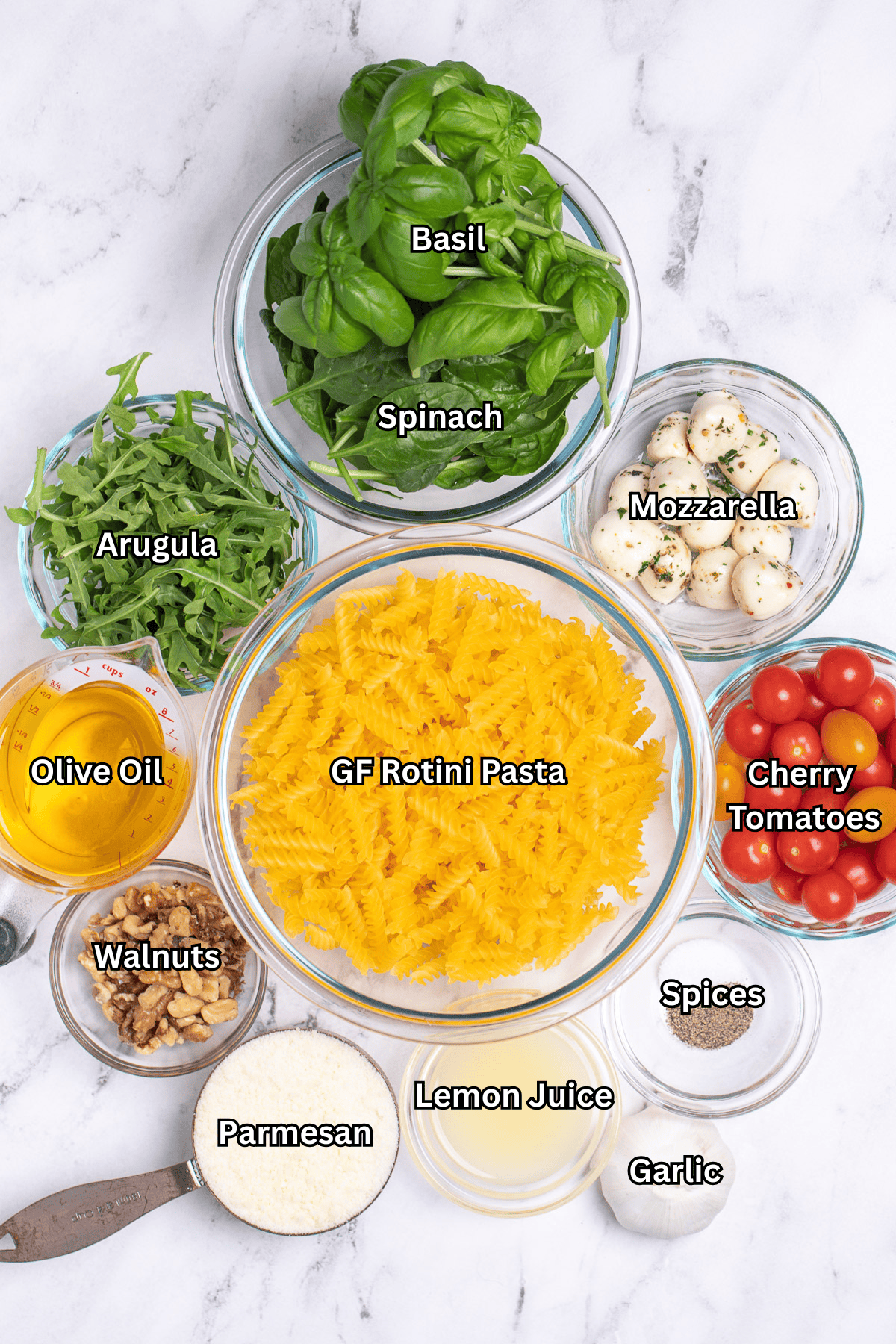 Individual ingredients for pesto pasta salad on a table.
