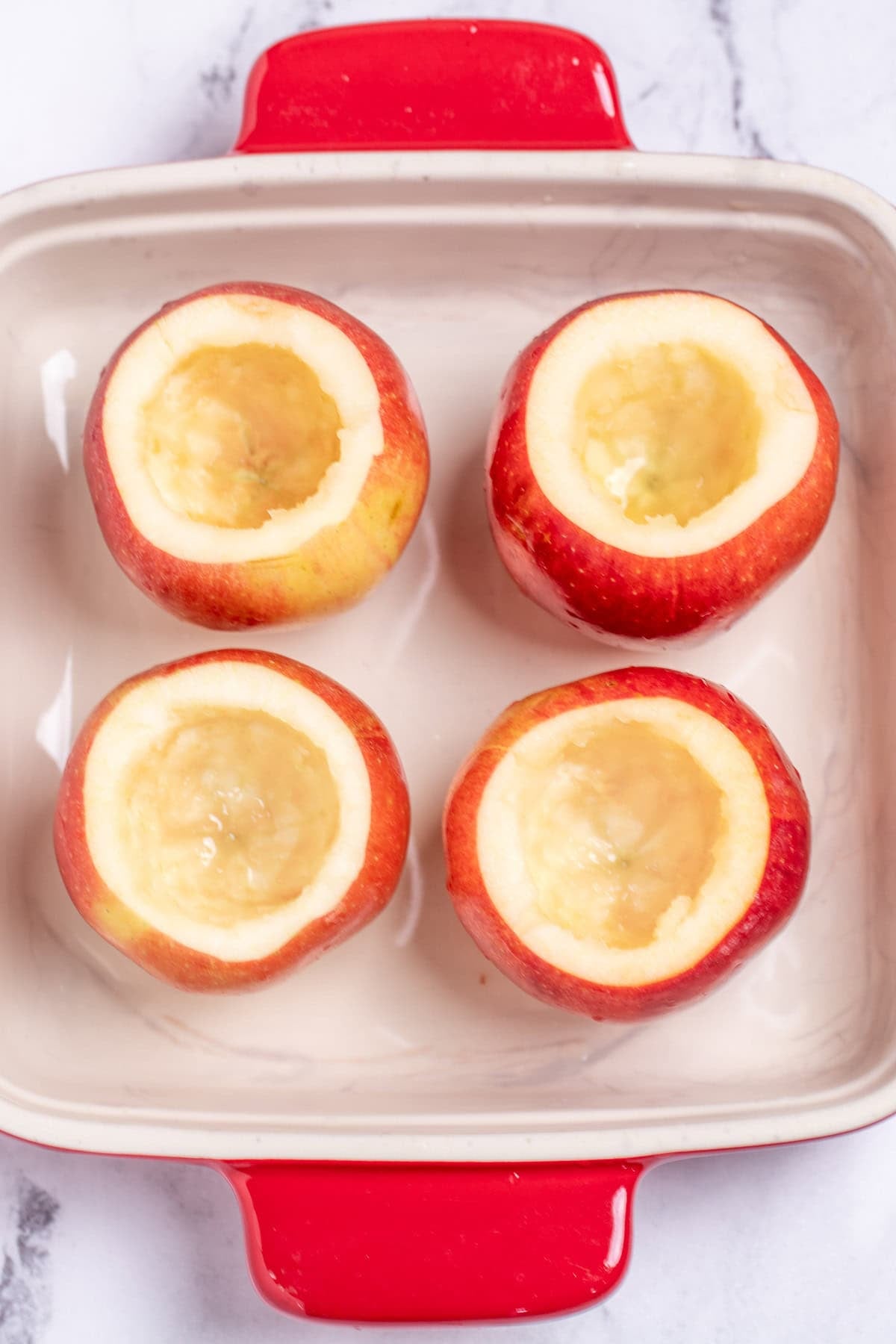 A baking dish with hallowed out apples standing up.