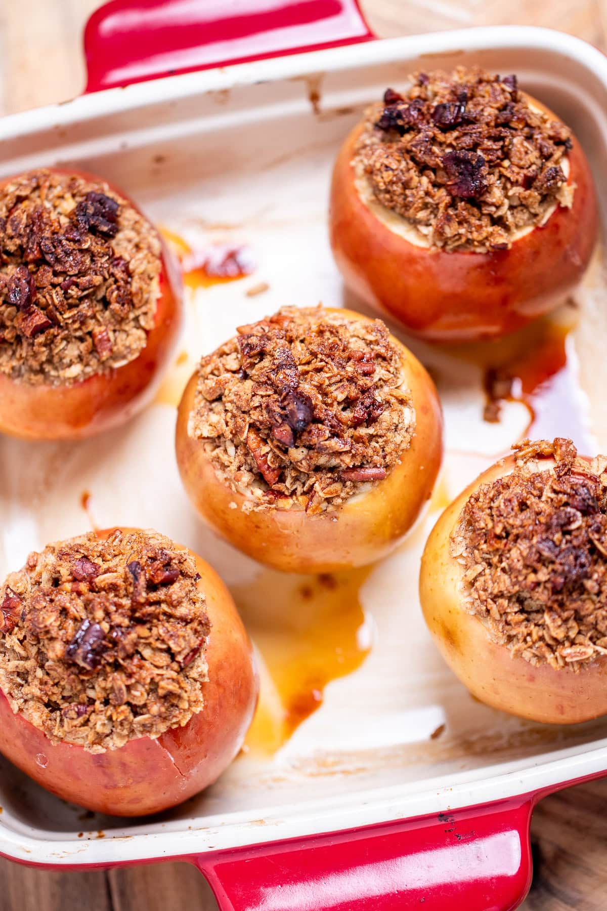 A baking dish with baked apples stuffed with cinnamon oatmeal that's toasted on top.