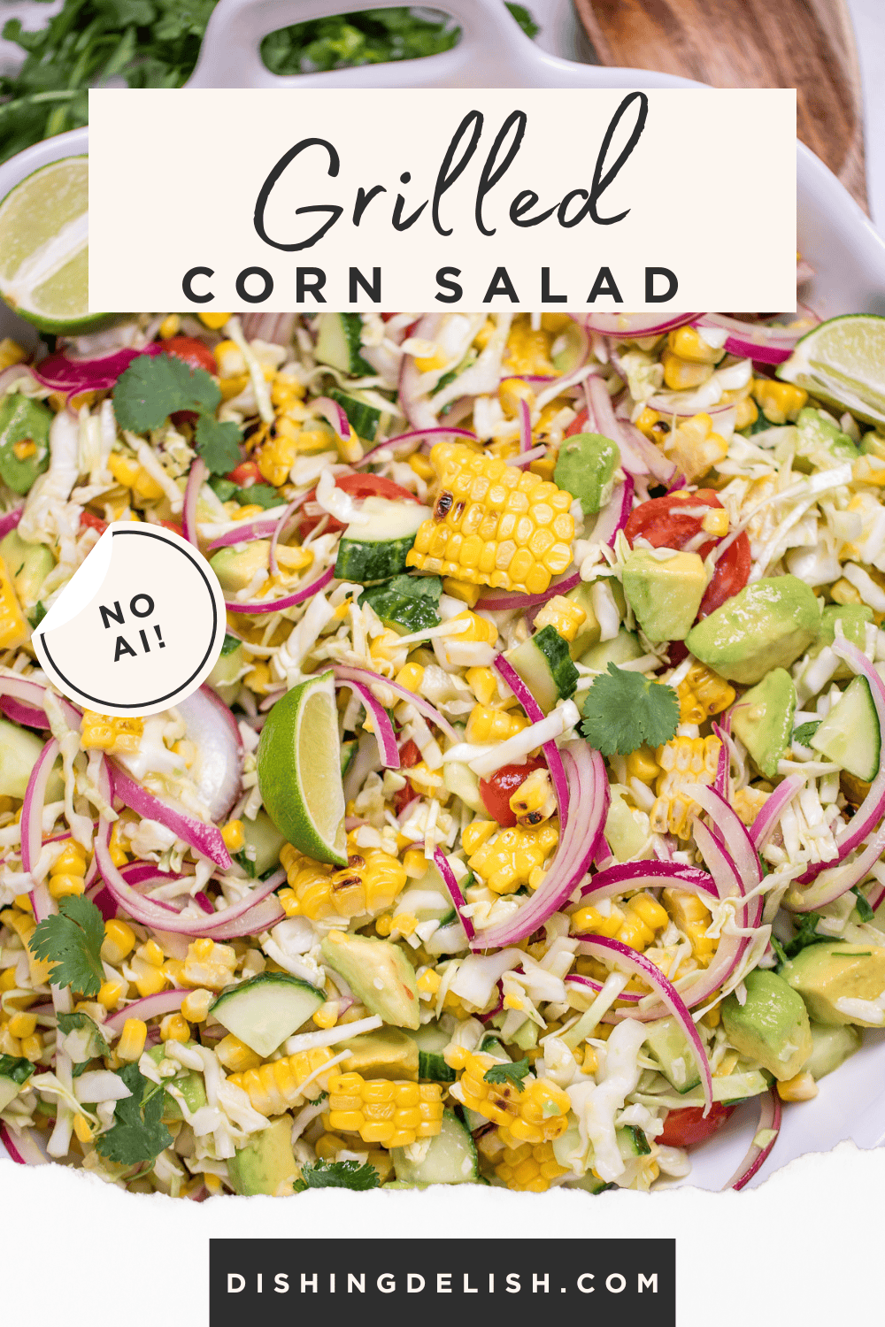Pinterest pin with a serving bowl full of summer corn salad with corn, avocado, red onion, cilantro, cabbage, and lime wedges, with a wooden spoon and cilantro behind the bowl.