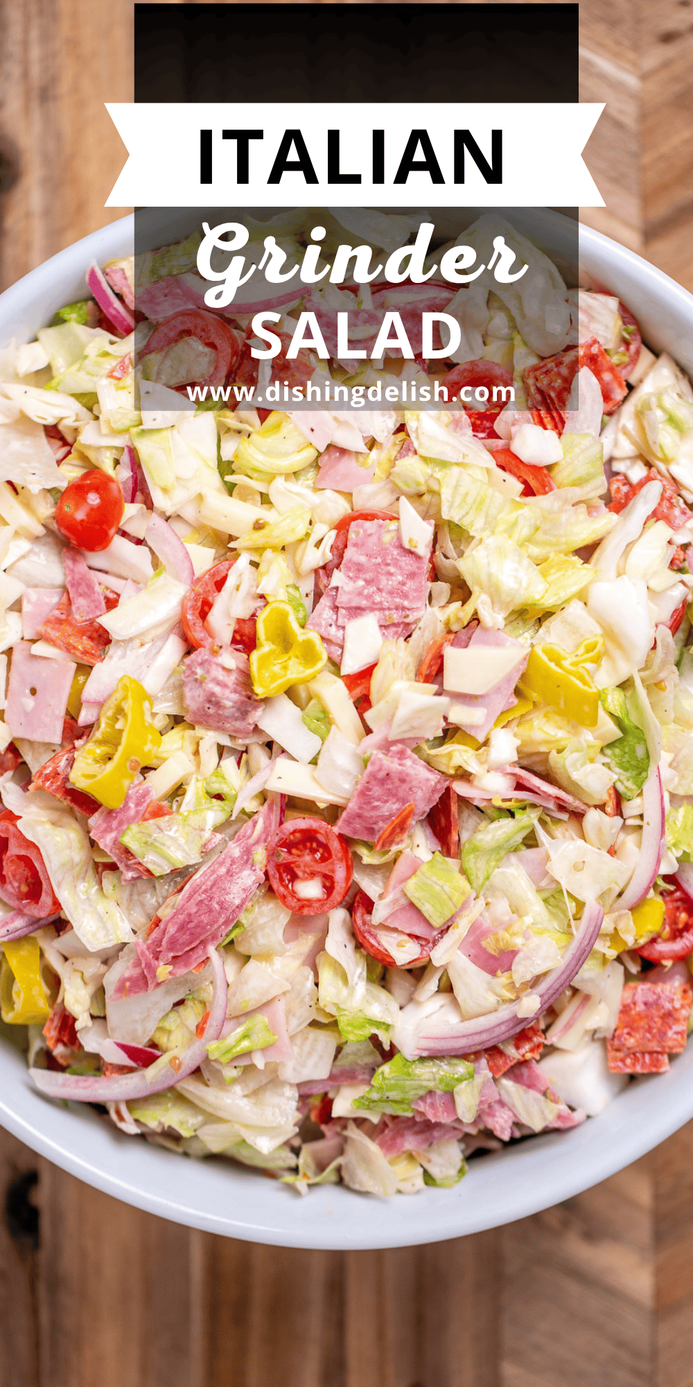 Pinterest pin with a bowl of Italian grinder salad (Italian sub salad) on a wooden cutting board.