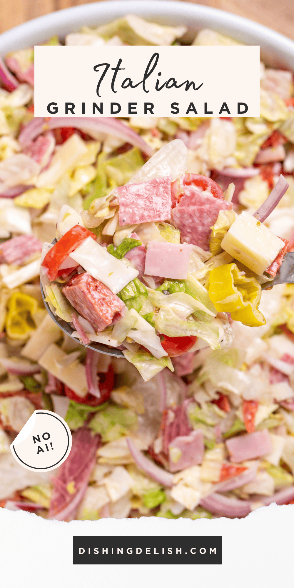 Pinterest pin with a spoon lifting Italian grinder salad out of a bowl, with lettuce, deli meat and cheese, red onion, and tomato in a creamy dressing.