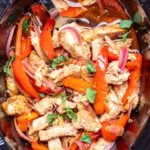 A crockpot of chicken fajitas topped with fresh cilantro.
