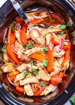 A crockpot of chicken fajitas topped with fresh cilantro.