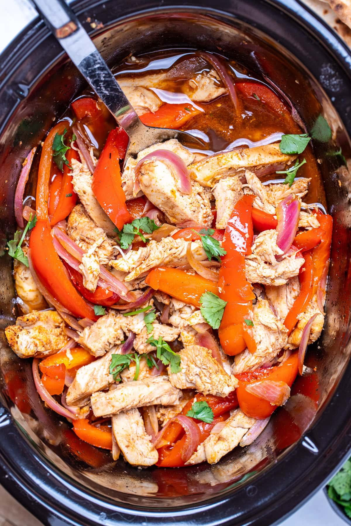 A crockpot of chicken fajitas topped with fresh cilantro.